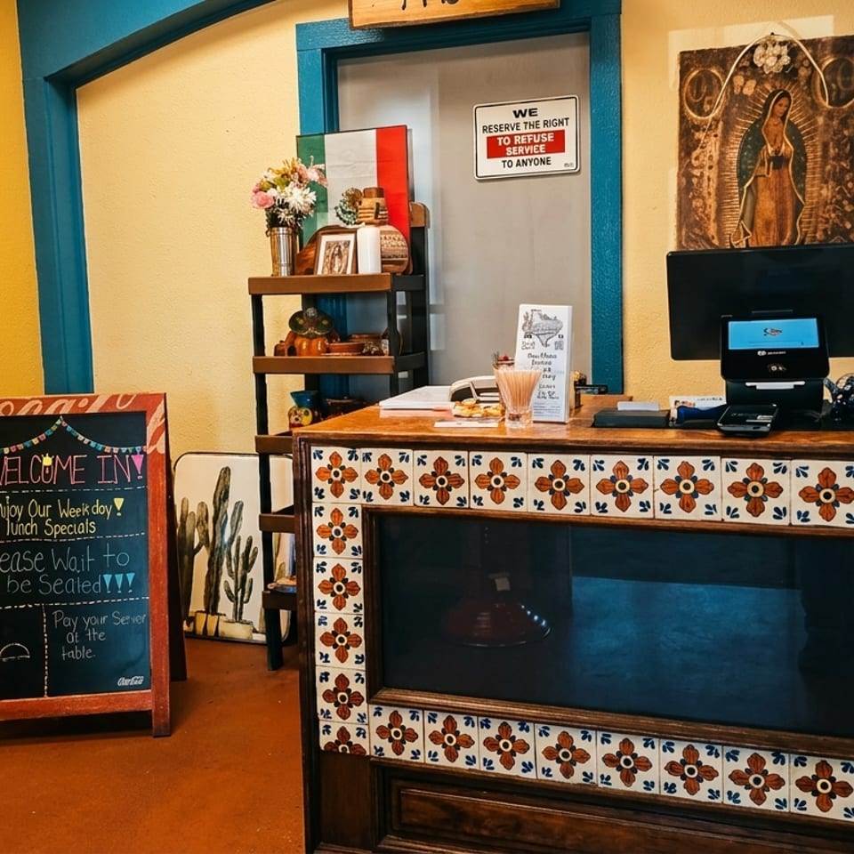 A vibrant Mexican restaurant interior with a tiled counter, chalkboard sign, and colorful decor.